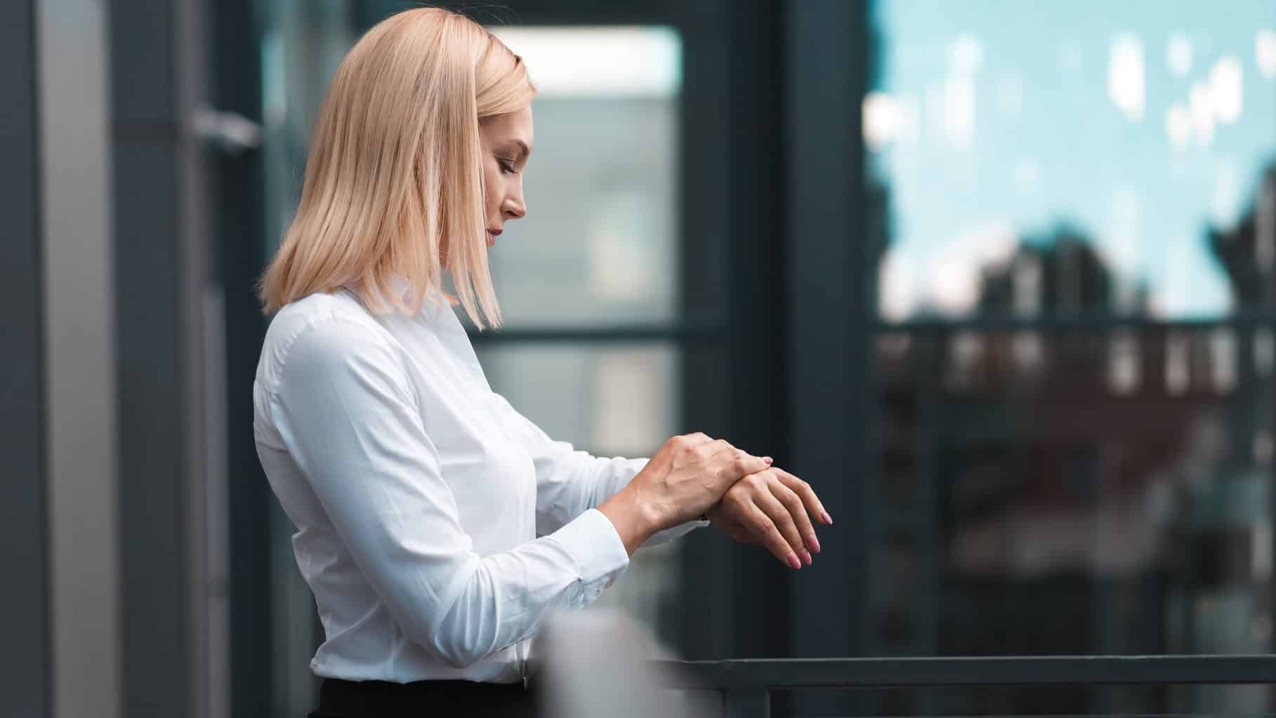 Beautiful business woman with white hair checks time on the watch