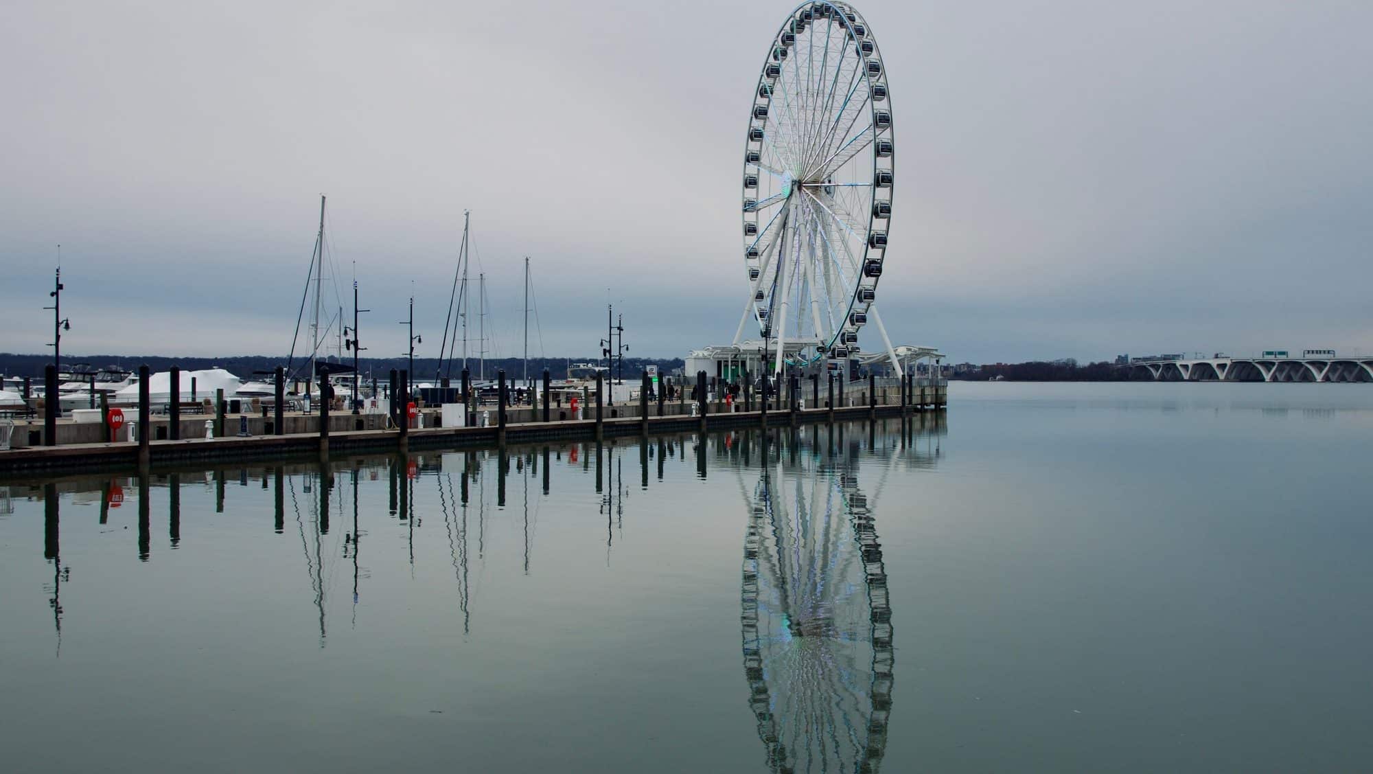 Ferris wheel at national harbor reflecting in bay on gray cloudy day