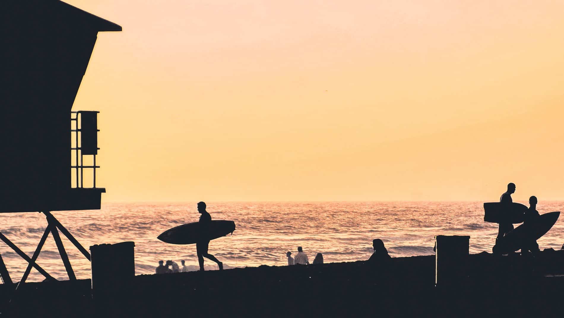 Silhouettes of surfers at the beach at sunset in Huntington Beach, California
