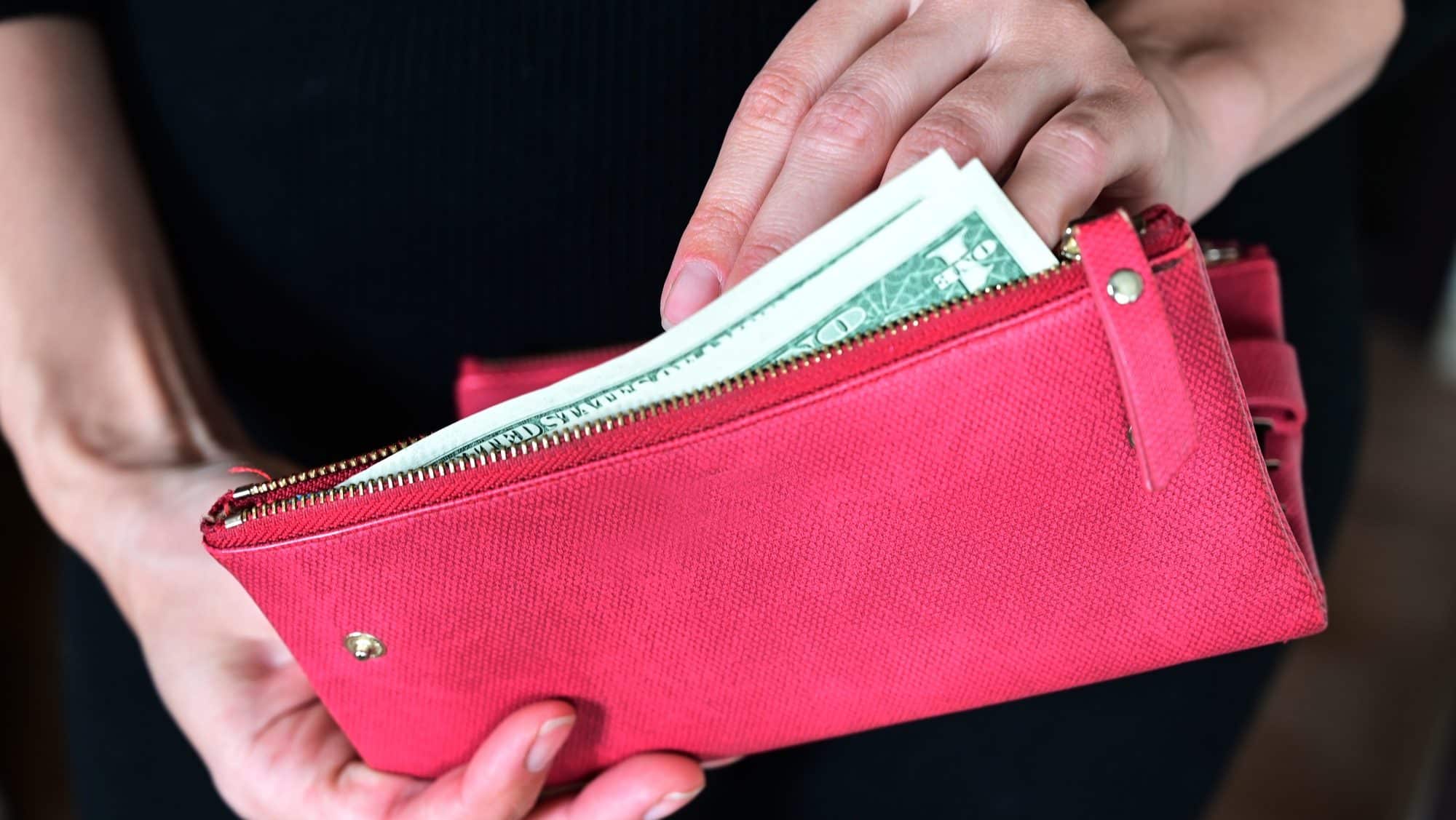 women's hands hold money, a purse with money